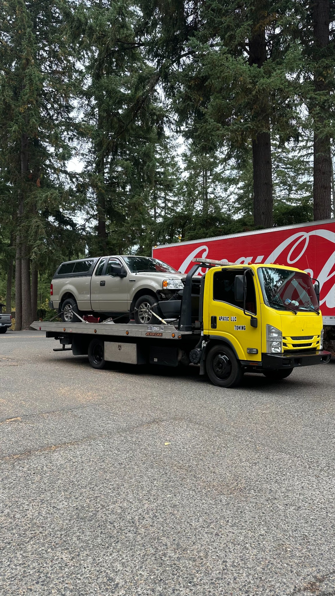 Yellow Apaxic towing truck transporting a pickup